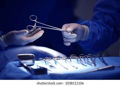 Surgeon Hand Picking Up An Instrument From Tray Of Surgical Instruments