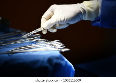 Surgeon Hand Picking Up An Instrument From Tray Of Surgical Instruments