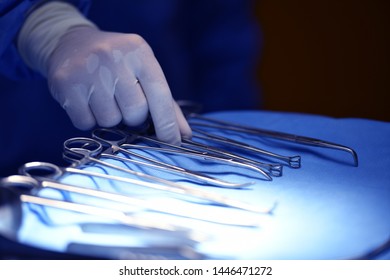 Surgeon Hand Picking Up An Instrument From Tray Of Surgical Instruments