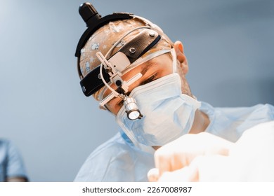 Surgeon with headlight is working in operating room. Blepharoplasty plastic surgery operation for modifying eye region. Surgeon is making incision with surgical knife - Powered by Shutterstock