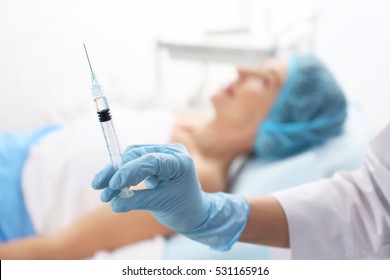 Surgeon holding syringe for facial injection, closeup