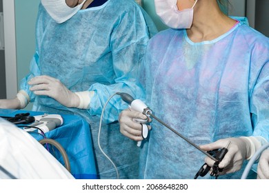 The surgeon holds a surgical laparoscopic manipulator in his hands. Selective focus. Minimally invasive laparoscopic proctological surgery. A doctor in uniform and gloves uses a surgical instrument.