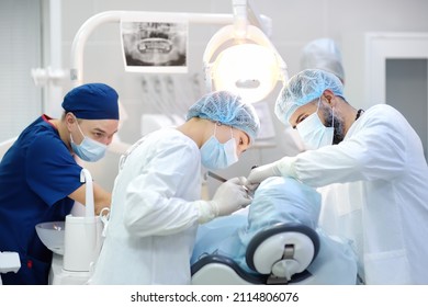 Surgeon and nurse during a dental operation.Anesthetized patient in the operating room.Installation of dental implants or tooth extraction in the clinic. General anesthesia during orthodontic surgery.