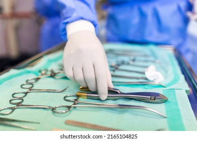 Surgeon picking up surgical tool from tray. Surgeon is preparing for surgery in operating room. He is in a hospital. - Powered by Shutterstock