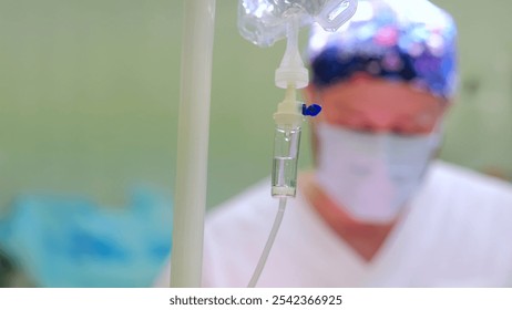 Surgeon in scrubs and mask is blurred in the background as an iv drip takes center stage, capturing the urgency of a busy hospital operating room scene - Powered by Shutterstock