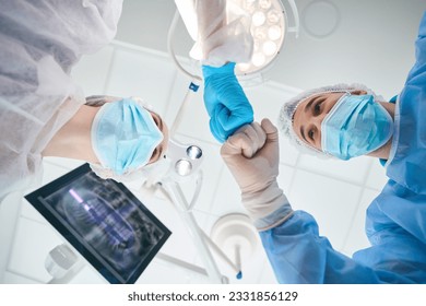 Surgeon stomatologist welcomes the assistant in the operating room - Powered by Shutterstock