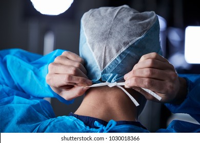 Surgeon tying surgical cap in preparation, back view - Powered by Shutterstock