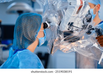 Surgeon uses microscope for delicate surgery. A surgeon, wearing surgical attire, uses a high-precision microscope to conduct a complex operation in an operating room. - Powered by Shutterstock