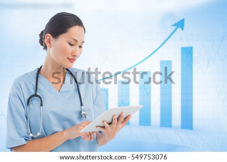Surgeon using digital tablet with group around table in hospital against blue data
