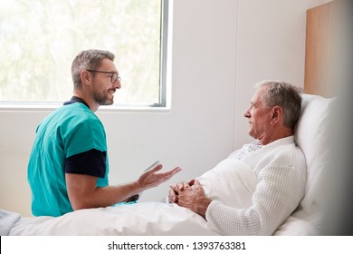 Surgeon Visiting And Talking With Senior Male Patient In Hospital Bed In Geriatric Unit