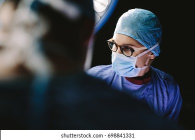 Surgeon wearing medical mask with medical team performing surgery in hospital operation theater.