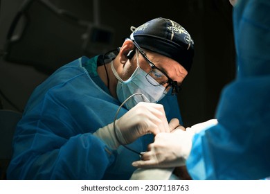 surgeon works in the operating room by the light of a lamp - Shutterstock ID 2307118763