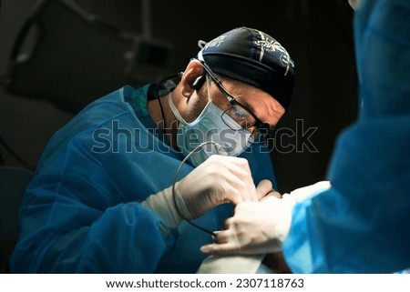 surgeon works in the operating room by the light of a lamp
