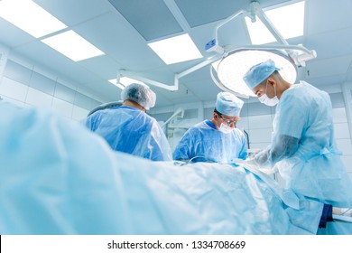 Surgeons in binocular lenses operate the patient lying under anesthesia in the operating room