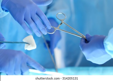 Surgeons Hands Holding And Passing Surgical Instrument To Other Doctor While Operating Patient. Resuscitation Medicine Team Holding Steel Medical Tools Saving Patient. Surgery And Emergency Concept