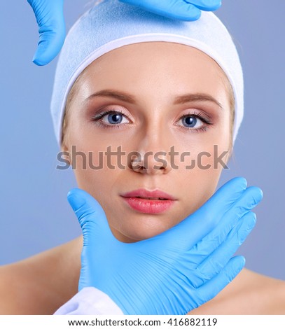 A surgeons hands touching a female face