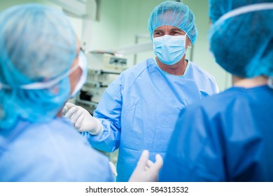 Surgeons interacting with each other in operation room at hospital. Healthcare workers in the Coronavirus Covid19 pandemic
 - Powered by Shutterstock