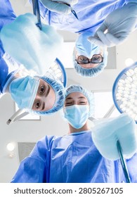 Surgeons looking down at the camera during a surgical procedure in a sterile operating theater. Medical team performing surgery, intense hospital environment. Healthcare, professional, surgery.