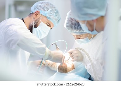 Surgeons and nurse during a dental operation.Anesthetized patient in the operating room.Installation of dental implants or tooth extraction in the clinic. General anesthesia during orthodontic surgery