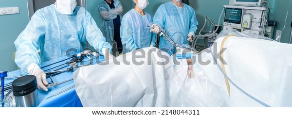 Surgeons operate on the patient in the operating\
room. A team of doctors performs laparoscopic surgery. Widescreen\
image. Banner.