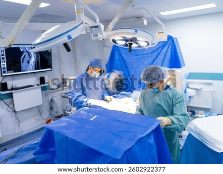 Surgeons operating in modern facility. Two surgeons focus on a surgical procedure in a sterile operating room with advanced medical technology.