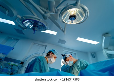 Chirurgen, die Patienten operieren. Zurück-Ansicht des Chirurgen-Teams betrachtet die Monitore während der Operation im Krankenhaus