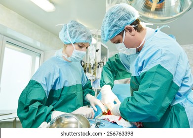 Surgeons Perfoming Surgery Operation Of Abdominal Cesarean Section During Child Delivery Birth At Clinic Operating Room