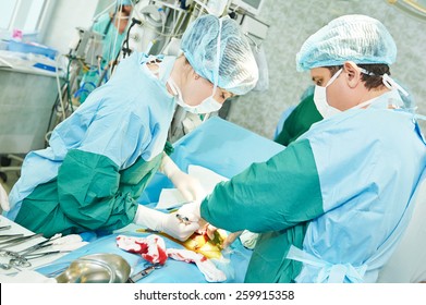 Surgeons Perfoming Surgery Operation Of Abdominal Cesarean Section During Child Delivery Birth At Clinic Operating Room