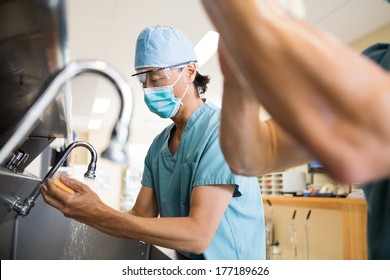 Surgeons scrubbing hands and arms before surgery in hospital