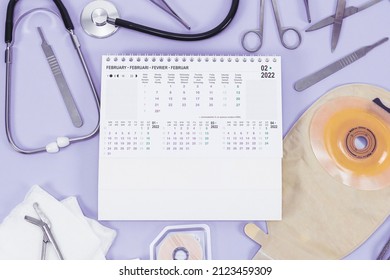 Surgeon's set: from a colostomy bag, surgical instruments, a stethoscope, bandages and an annual calendar 2022 on a light lilac background, flat lay .Colon cancer concept, surgery and planning operati