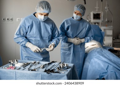 Surgeons in uniform prepare sterile medical instruments for surgery, ready to operate a patient in the operating room. Concept of invasive treatment - Powered by Shutterstock