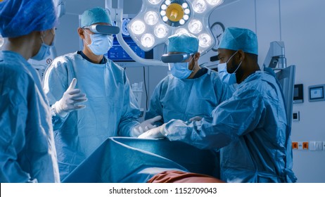 Surgeons Wearing Augmented Reality Glasses Performing State Of The Art Surgery In High Tech Hospital. Doctors And Assistants Working In Operating Room.