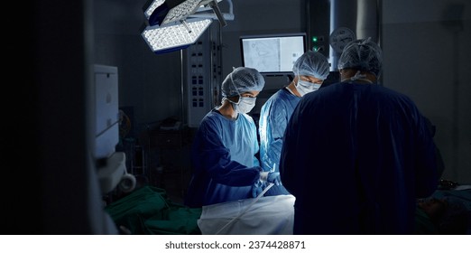 Surgery, dark room and doctors with healthcare, teamwork and support with wellness, safety and emergency. People, medical professionals or group with cooperation, theatre and medicine in hospital - Powered by Shutterstock