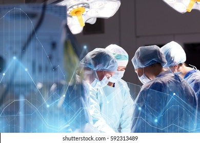 surgery, healthcare, medicine and people concept - group of surgeons at operation in operating room at hospital with virtual diagram projection