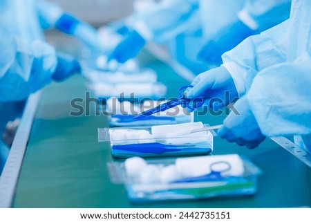 Surgery kit on conveyor line, closeup of medical staff gloved hands sorting blue med instrument scissors, tool of doctor pharmacy, clear light toning. Foto stock © 