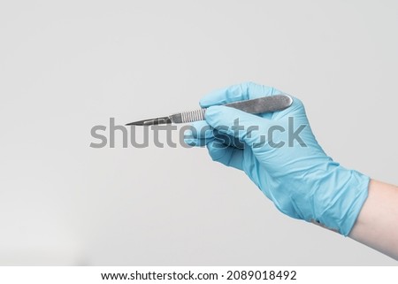 surgery, medicine and people concept - close up of surgeons hands with scalpel at operation in operating room at hospital