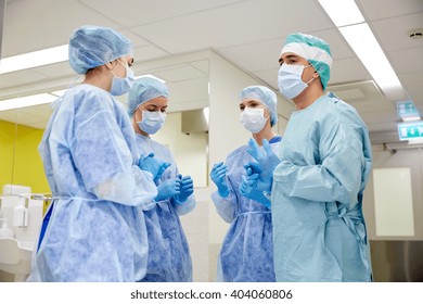 surgery, medicine and people concept - group of surgeons in operating room at hospital talking and preparing to operation - Powered by Shutterstock