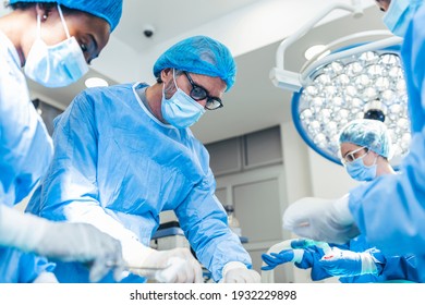 Surgery operation. Group of surgeons in operating room with surgery equipment. Medical background, selective focus. Surgeon team working together while operation - Shutterstock ID 1932229898