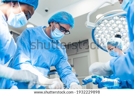 Surgery operation. Group of surgeons in operating room with surgery equipment. Medical background, selective focus. Surgeon team working together while operation