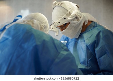 Surgery. Profile View Of The Chief Surgeon With A Lamp On His Head.