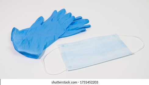 Surgical Face Mask And Blue Nitrile Gloves On White Table. PPE For Virus Prevention.