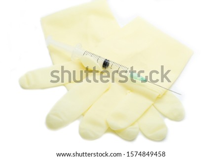 Surgical glove, mask, cap and syringe on white background.