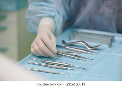 Surgical Instruments In The Operating Room. A Surgeon Preparing For A Tooth Implantation And Sinus Lifting Operation
Dental Probe, Curettes Tweezers, Scalpel, Needle Holder, Rasps On Instrument Table.