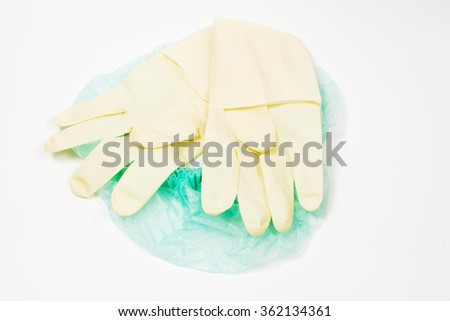 Surgical latex glove, mask and cap on white background.