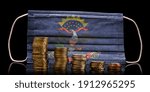 A surgical mask with the flag of North Dakota behind some descending stacks of various coins.(series)