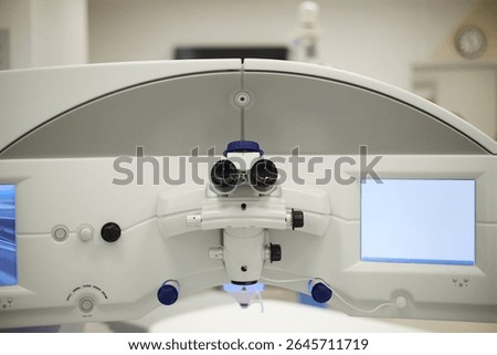 Surgical microscope positioned in modern operating room showing advanced optical lenses and control panels used for precision medical procedures in hospital environment