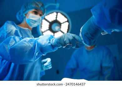 Surgical nurse giving sterile equipment to doctor surgeon during operation - Powered by Shutterstock