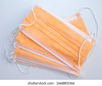Surgical protective mask of orange color for protection against flu and other diseases. Medical respiratory bandage face on white background. Prevention of the spread of virus and epidemic
