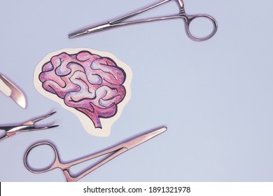 Surgical Scalpel And Clamps Are On Table. Painted Human Brain On Blue Background. Concept Of Brain Surgery. Mockup