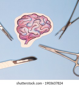 Surgical Scalpel And Clamps Are On Table. Painted Human Brain On Blue Background. Concept Of Brain Surgery. Square Image